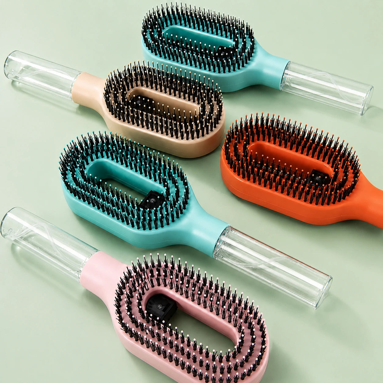 Set of five hairbrushes in different colors on a light green background